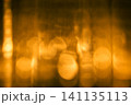 ガラスコップ越しに見えるロウソクの光をぼかした抽象背景 141135113
