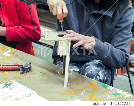 Parent helping child to hammer details of a wooden toy craft during Home Depot kids workshop - June 6, 2026 Federal Way WA, USA Parent helping child to hammer details of a wooden toy craft during Home Depot kids workshop - June 6, 2026 Federal Way WA, USA 141135212