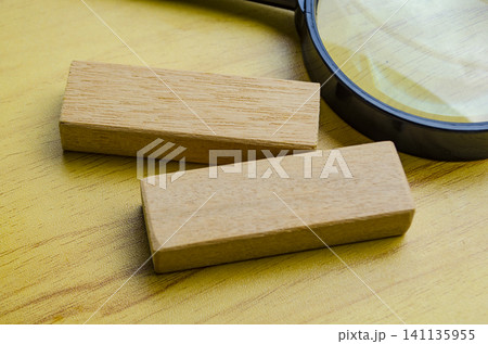 Natural wooden blocks beside a magnifying glass on a wooden tabletop with simple educational styling 141135955