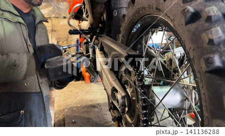 Professional mechanic repairing detail of motorcycle at workplace. Male repairer fixing moto at workshop. Adult repairman mending vehicle at garage. Concept of maintenance service. Slow motion 141136288