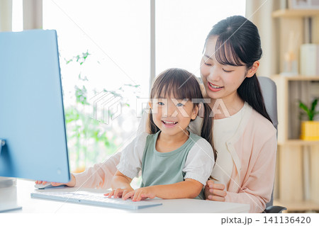 リビングで仕事をするママと遊ぶこども リビングで仕事をするママと遊ぶこども 141136420