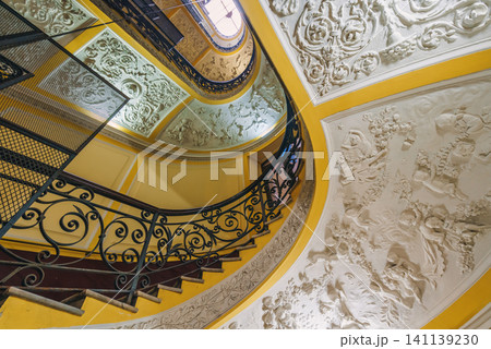 Naples, Italy - November 5, 2018, Panoramic view of antique curved staircase decorated with stucco with wrought iron railings with a floral pattern at Galleria Umberto I, without people, Naples, Italy Naples, Italy - November 5, 2018, Panoramic view of antique curved staircase decorated with stucco with wrought iron railings with a floral pattern at Galleria Umberto I, without people, Naples, Italy 141139230