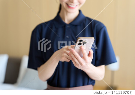 スマホで仕事を管理する清掃業の女性 スマホで仕事を管理する清掃業の女性 141139707