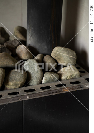 Sauna heater with smooth natural stones radiating warmth and promoting relaxation in a wellness spa environment Sauna heater with smooth natural stones radiating warmth and promoting relaxation in a wellness spa environment 141141730