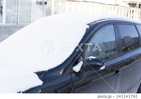 Black car covered in thick snow during winter season, parked outdoors experiencing cold weather 141141742