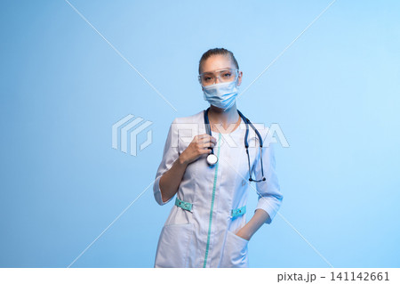 Medical worker standing, looking at camera, wearing protective equipment and scrubs, symbolizing health and protection Medical worker standing, looking at camera, wearing protective equipment and scrubs, symbolizing health and protection 141142661