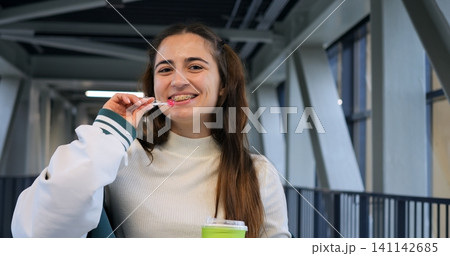 Joyful indoor moment. Cheerful woman enjoying casual leisure. Relaxed woman smiling with straw indoors. Spontaneous joyful expression captured of woman with cup and playful smile indoors Joyful indoor moment. Cheerful woman enjoying casual leisure. Relaxed woman smiling with straw indoors. Spontaneous joyful expression captured of woman with cup and playful smile indoors 141142685
