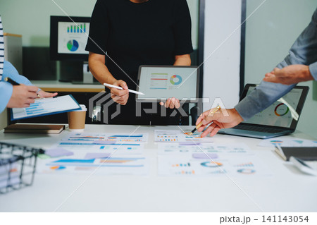 Business documents on office table with smart phone and calculator digital tablet and graph business with social network diagram and two colleagues discussing data working 141143054