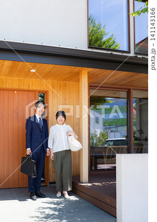 マイホームの前に立つ若い夫婦 141143166