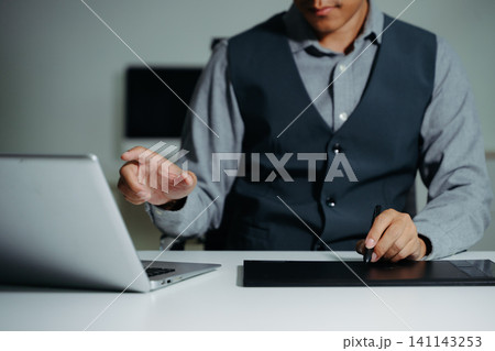 Confident businessman working on laptop, tablet and smartphone at her workplace at modern office. Confident businessman working on laptop, tablet and smartphone at her workplace at modern office. 141143253