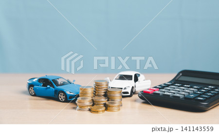 Toy cars, coin stacks, and calculator on desk with copy space, representing auto finance comparison, car insurance, vehicle loan payment, purchase planning, and transportation cost. Toy cars, coin stacks, and calculator on desk with copy space, representing auto finance comparison, car insurance, vehicle loan payment, purchase planning, and transportation cost. 141143559