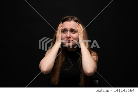 Stressed woman experiencing headache, holding head in hands, feeling overwhelmed with anxiety, pressure, and frustration 141143564