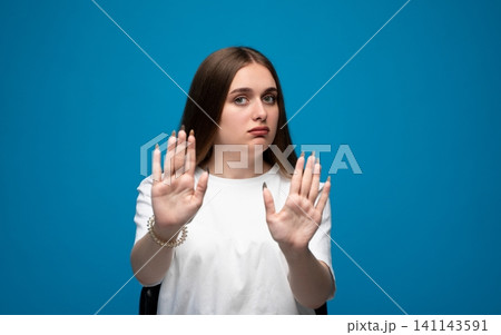 Young woman making a stop gesture, showing refusal, denial, and disagreement with a serious expression 141143591