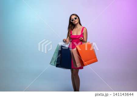 Young woman confidently posing with shopping bags, showcasing a vibrant consumer lifestyle and successful retail experience Young woman confidently posing with shopping bags, showcasing a vibrant consumer lifestyle and successful retail experience 141143644