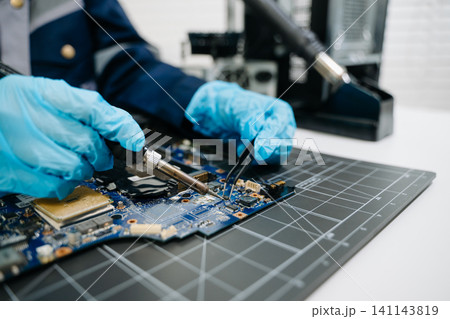 technician soldering microchip on circuit board, highlighting precision electronics repair, hardware maintenance, and advanced technology work. technician soldering microchip on circuit board, highlighting precision electronics repair, hardware maintenance, and advanced technology work. 141143819