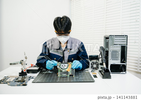 expert soldering a green PCB board using precision tools. Ideal for electronics, circuit repair, engineering, tech 141143881
