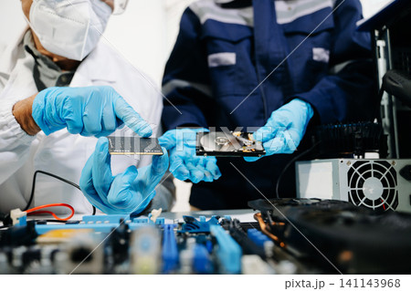 Technicians repairing computer hardware, testing components and upgrading PC systems. Technology service, electronics engineering and IT support concept. Technicians repairing computer hardware, testing components and upgrading PC systems. Technology service, electronics engineering and IT support concept. 141143968