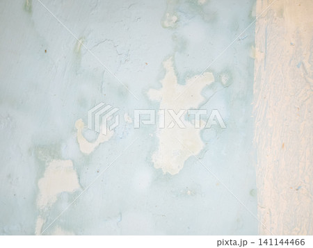 Abstract background of a weathered and distressed wall with peeling paint and plaster in faded light blue and beige tones, showcasing aged texture and grunge details. Abstract background of a weathered and distressed wall with peeling paint and plaster in faded light blue and beige tones, showcasing aged texture and grunge details. 141144466