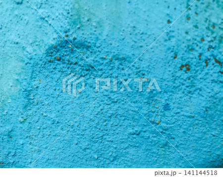 Abstract background of a weathered and distressed wall with peeling paint and plaster in faded light blue and beige tones, showcasing aged texture and grunge details. 141144518