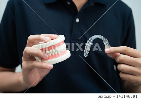 Man holding invisible aligner orthodontic retainer for dental teeth straightening. Man holding invisible aligner orthodontic retainer for dental teeth straightening. 141146591