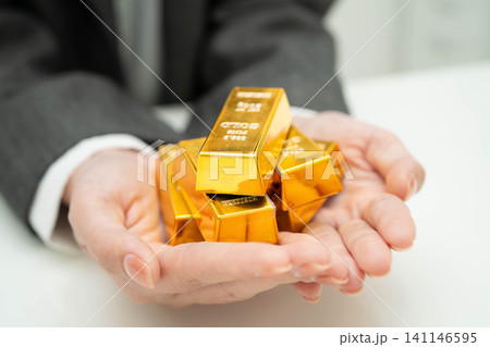Asian woman holding gold bar in finance business. Asian woman holding gold bar in finance business. 141146595