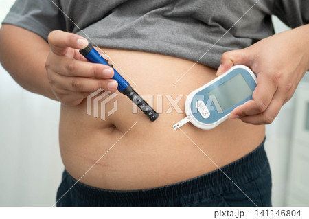 Asian woman injecting herself diabetes injecting insulin in stomach at home. 141146804