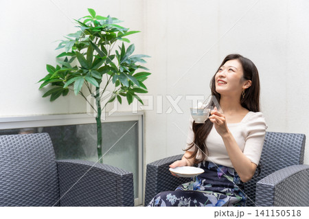 民泊施設のテラスでコーヒーを飲みながらリラックスする旅行中の若い女性 民泊施設のテラスでコーヒーを飲みながらリラックスする旅行中の若い女性 141150518