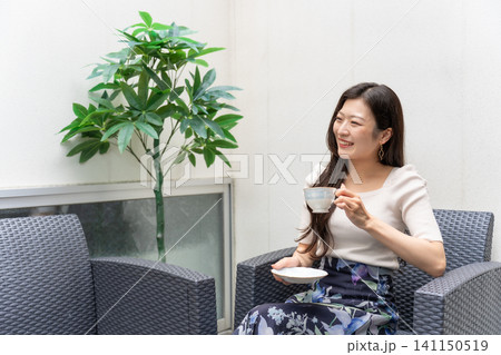 民泊施設のテラスでコーヒーを飲みながらリラックスする旅行中の若い女性 民泊施設のテラスでコーヒーを飲みながらリラックスする旅行中の若い女性 141150519