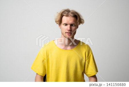 Young man with light brown hair showing a humorous facial expression, crossing his eyes and looking down, conveying a comical mood and playful attitude Young man with light brown hair showing a humorous facial expression, crossing his eyes and looking down, conveying a comical mood and playful attitude 141150880
