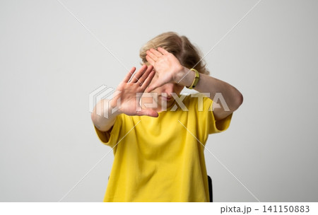 Young man covering face protecting privacy, shielding from public attention, denying access, refusing interaction, gesturing stop and defense 141150883