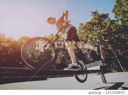 Bmx rider performing tricks at skatepark. 141150937