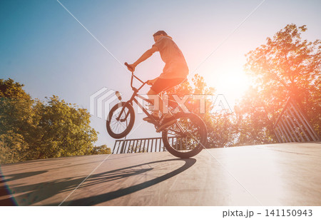 Bmx rider performing tricks at skatepark. 141150943