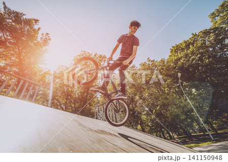 Bmx rider performing tricks at skatepark. 141150948