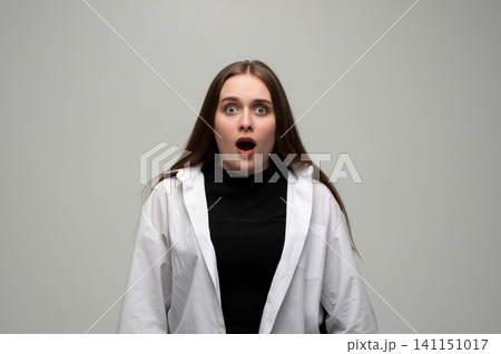 Young woman with wide eyes and open mouth showing surprise, shock, and disbelief in a studio setting Young woman with wide eyes and open mouth showing surprise, shock, and disbelief in a studio setting 141151017
