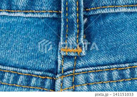Blue denim jeans texture with belt loop and orange stitching close up Blue denim jeans texture with belt loop and orange stitching close up 141151033