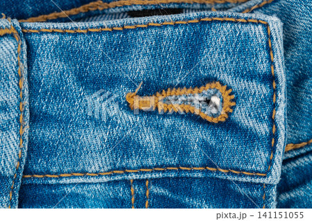 Denim fabric closeup with buttonhole and orange stitching Denim fabric closeup with buttonhole and orange stitching 141151055