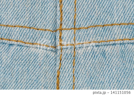 Macro view blue denim fabric with orange stitching, inside out or wrong side. Detailed texture of jeans cloth showing sewing seam. Concept of textile industry, clothing manufacture. Apparel background Macro view blue denim fabric with orange stitching, inside out or wrong side. Detailed texture of jeans cloth showing sewing seam. Concept of textile industry, clothing manufacture. Apparel background 141151056