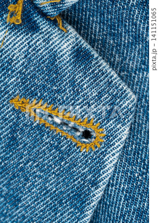 Close-up of buttonhole in blue denim fabric. Macro texture of jeans cloth with yellow contrast stitching. Fashion textile detail for garment manufacturing and dressmaking material background Close-up of buttonhole in blue denim fabric. Macro texture of jeans cloth with yellow contrast stitching. Fashion textile detail for garment manufacturing and dressmaking material background 141151065