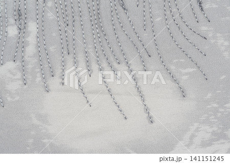 Closeup of stitched fabric with diagonal thread pattern on textured gray background Closeup of stitched fabric with diagonal thread pattern on textured gray background 141151245