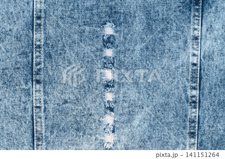 Ripped blue denim fabric texture with seams and distressed details Ripped blue denim fabric texture with seams and distressed details 141151264