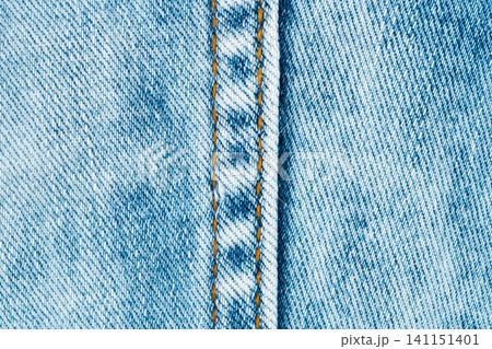 Blue denim fabric texture with vertical seam and orange stitching Blue denim fabric texture with vertical seam and orange stitching 141151401