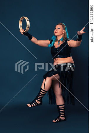 Extraordinary dancer stands on one leg in time with rhythmic strike of tambourine held in one hand Extraordinary dancer stands on one leg in time with rhythmic strike of tambourine held in one hand 141151666