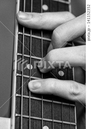 Musician hand playing six string acoustic classical guitar chord on fretboard. Monochrome shot Musician hand playing six string acoustic classical guitar chord on fretboard. Monochrome shot 141152352