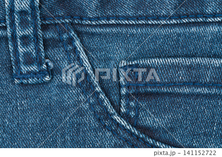 Close up view of blue denim jeans pocket with double stitch. Texture of casual cotton fabric textile. Durable apparel material for clothing industry manufacturing and fashion design concept Close up view of blue denim jeans pocket with double stitch. Texture of casual cotton fabric textile. Durable apparel material for clothing industry manufacturing and fashion design concept 141152722