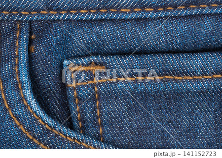 Closeup of blue denim fabric with orange stitching and pocket detail Closeup of blue denim fabric with orange stitching and pocket detail 141152723