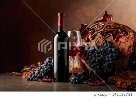 Bottle of red wine with blue grapes on a brown background. Bottle of red wine with blue grapes on a brown background. 141152751