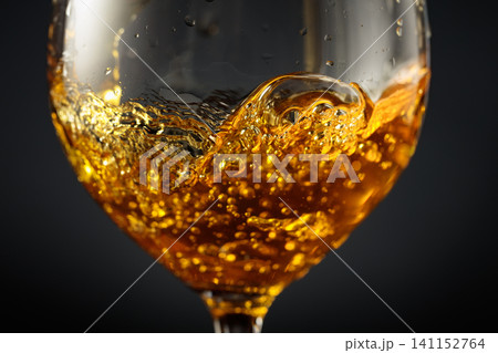 White wine of rich amber color being poured into a glass. White wine of rich amber color being poured into a glass. 141152764
