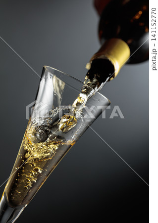 White sparkling wine is poured from a bottle into a glass. White sparkling wine is poured from a bottle into a glass. 141152770