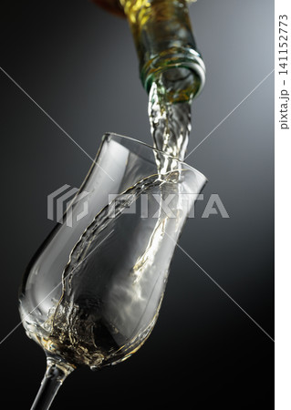Whiskey is poured from a bottle into a glass. Whiskey is poured from a bottle into a glass. 141152773