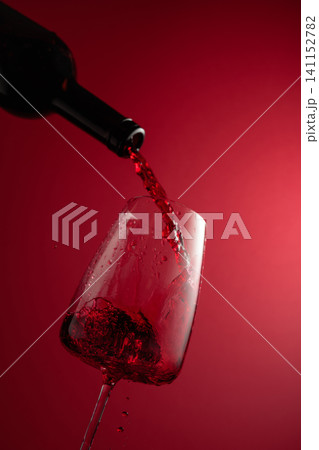 Pouring red wine from a bottle into a glass. Pouring red wine from a bottle into a glass. 141152782